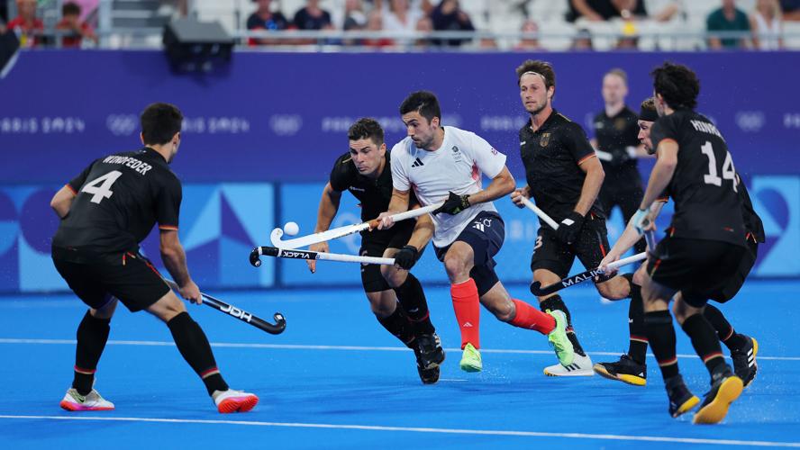 Lee Morton of Great Britain controls the ball under pressure from Germany during the men's Pool A match on day seven of the Paris Olympics at Stade Yves Du Manoir on August 02, 2024.